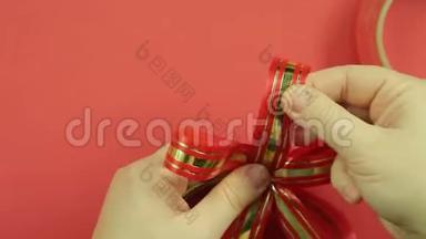 女人`双手伸直了粉红色丝带礼物蝴蝶结的花瓣。 红色背景
